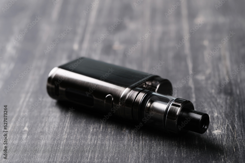 An electronic cigarette for smoking nicotine on a dark wooden background An electronic cigarette for smoking nicotine on a dark wooden background