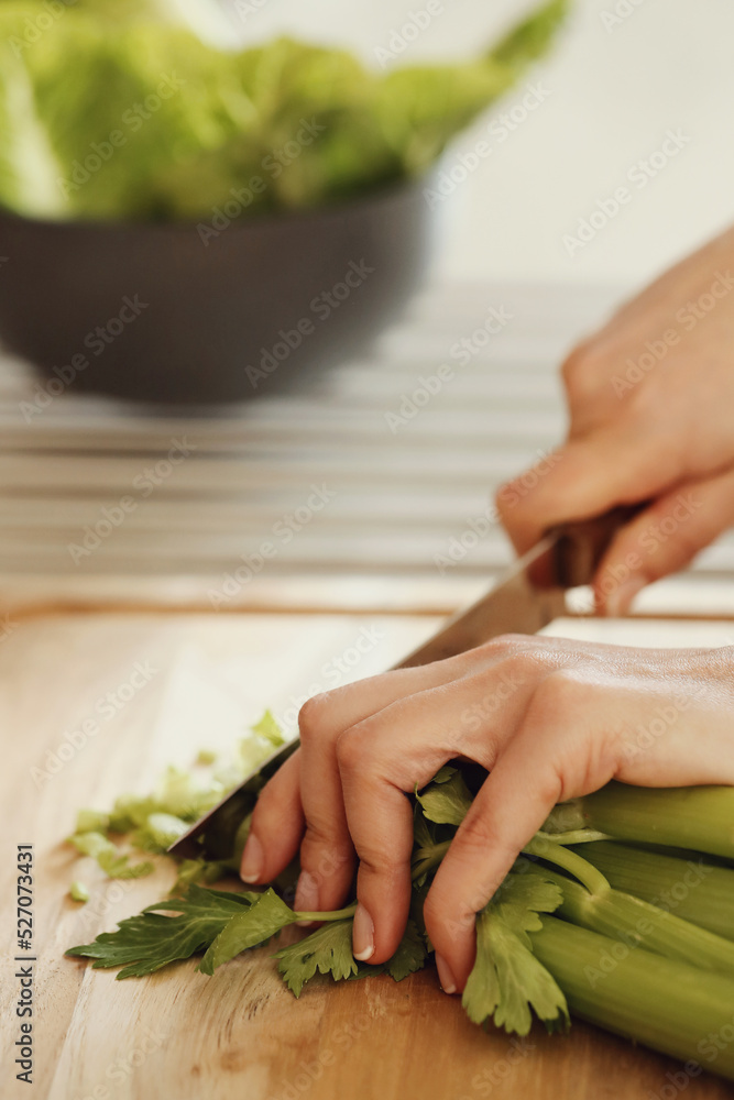Women’s hands cut celery on a wooden cutting board Women’s hands cut celery on a wooden cutting board