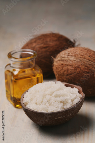 A glass jar of oil with sea salt and two whole coconuts