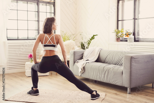 Professional female fitness trainer in sportwear doing yoga exercise at home