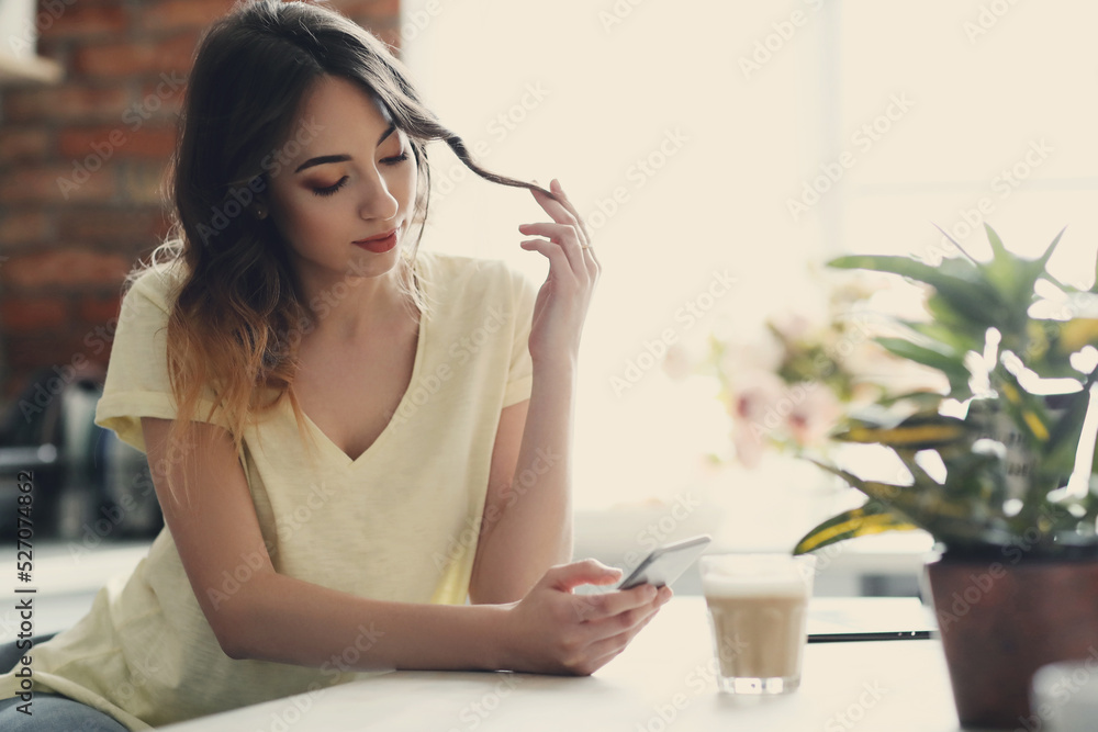 Young, charming, brunette girl holding modile phone in the kitchen at home Young, charming, brunette girl holding modile phone in the kitchen at home