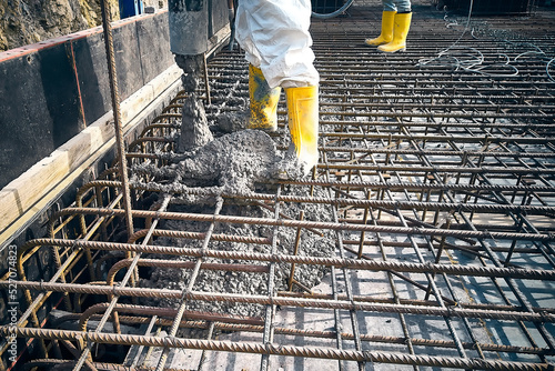 Contractor is casting concrete using concrete pump tube. Cement works on a construction site. Construction workers dressed in uniform pour a concrete to formwork photo