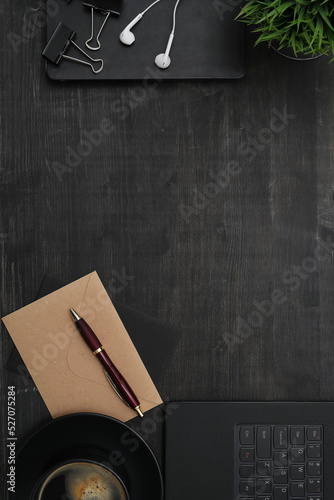 Top view of a cup of dark coffee with pen and earphones isolated on a dark marble surface 