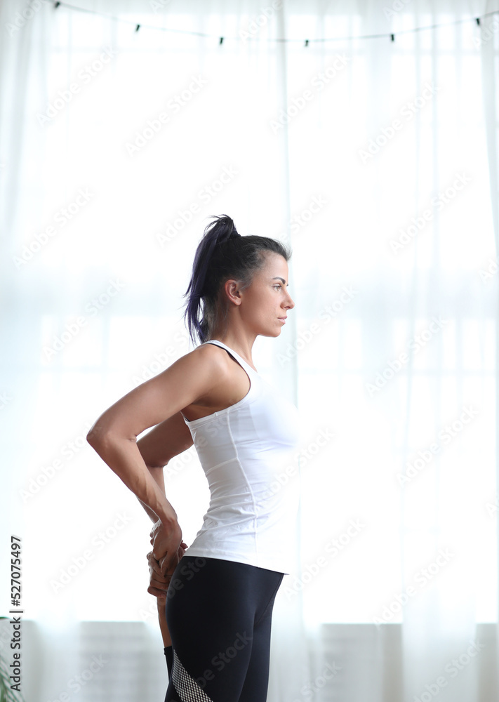 Beautiful female fitness trainer stretching legs after exercises on yoga mat Beautiful female fitness trainer stretching legs after exercises on yoga mat