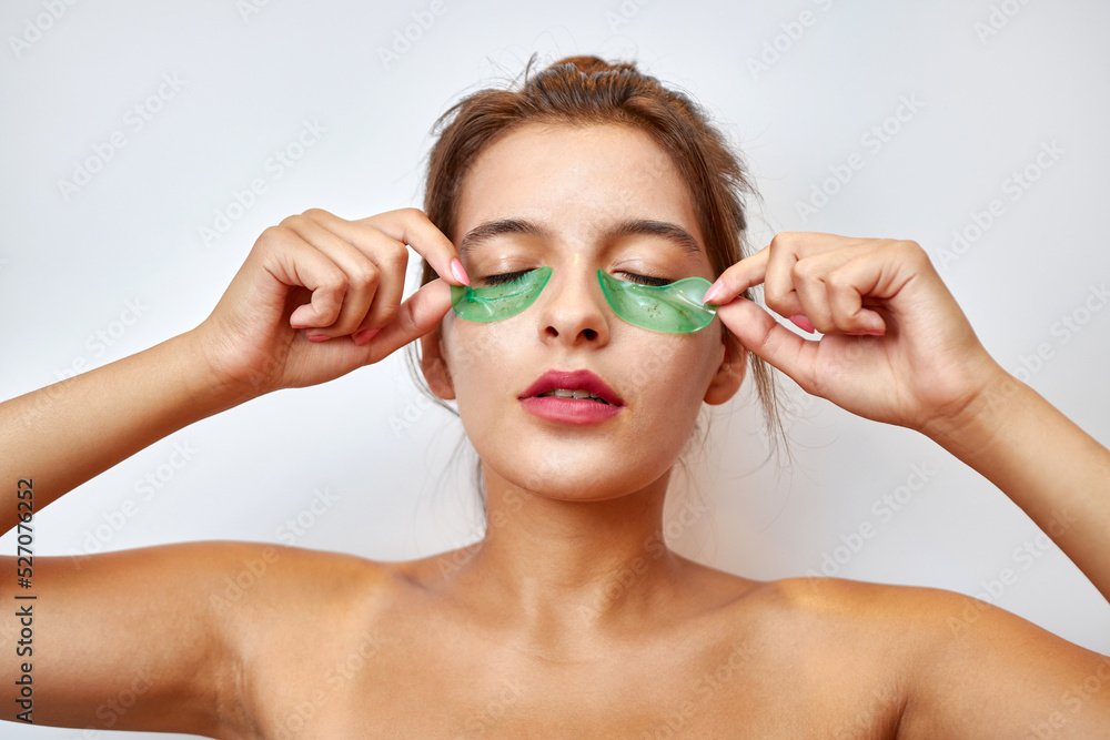The girl uses collagen hydrogel patches under her eyes. Beauty concept, cosmetics for skin care around the eyes, lifting. Beauty salon. Wrinkle removal. The girl uses collagen hydrogel patches under her eyes. Beauty concept, cosmetics for skin care around the eyes, lifting. Beauty salon. Wrinkle removal.