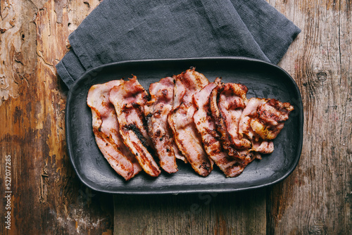 Hot fried bacon slices in a cast iron plate