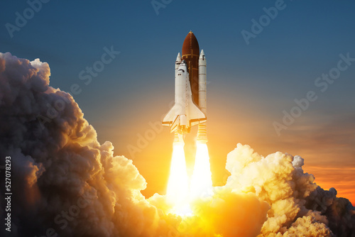 Fototapeta Naklejka Na Ścianę i Meble -  Spaceship lift off. Space shuttle with smoke and blast takes off into space on a background of sunset. Successful start of a space mission. Elements of this image furnished by NASA.