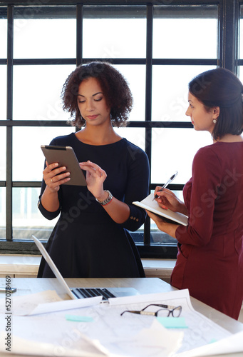 Women executives at the office discuss some documents.