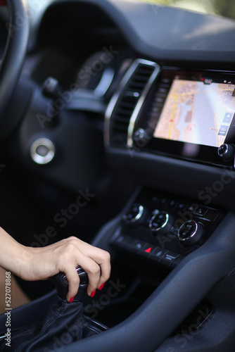 A young woman sitting in a private car, holding her hand on the gear 