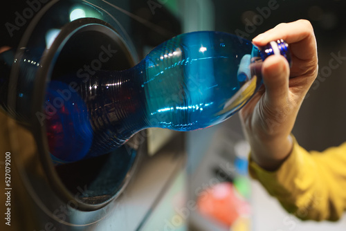 Fotografie Woman puts bottle in automatic bottle recycling machine