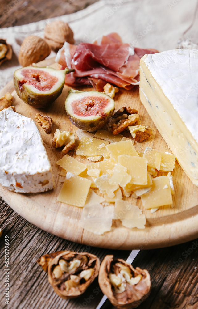 Delicious food with cheese , figs and nuts on a wooden surface.