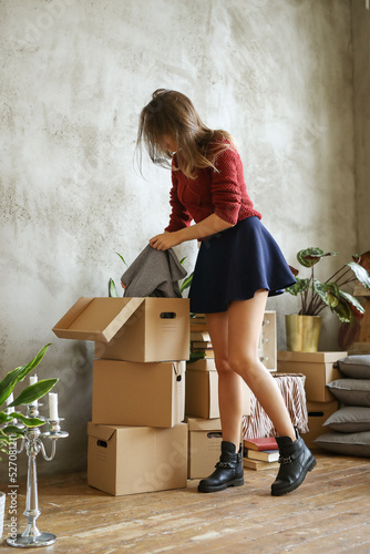 Full size photo cute girl in black skirt folds things into cardboard boxes
