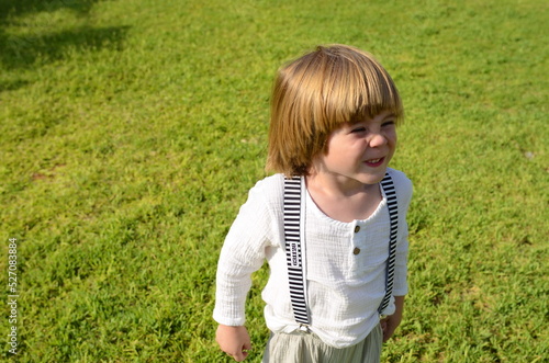 A little boy in a white shirt and striped suspenders makes faces. Football fan. Funny naughty kid. Children's revolution. © ShU studio