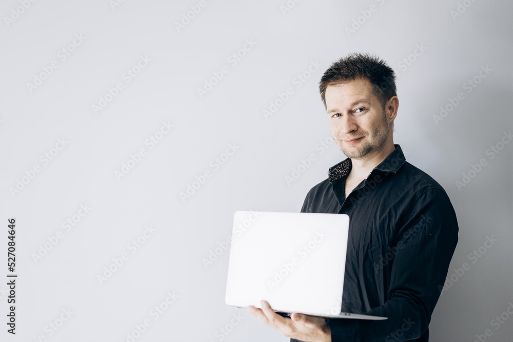 Confident IT specialist in black shirt holding laptop and smiling. Confident IT specialist in black shirt holding laptop and smiling.