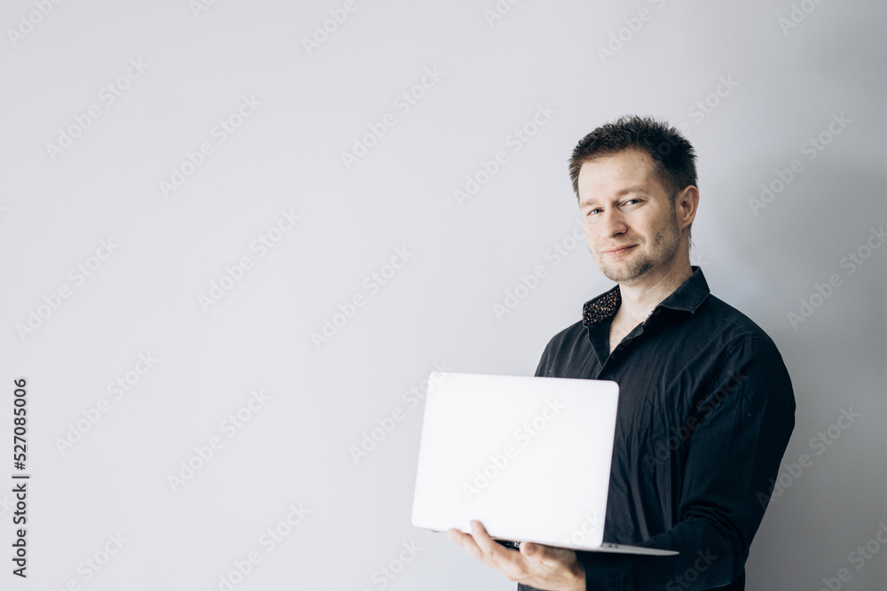 Confident IT specialist in black shirt holding laptop and smiling. Confident IT specialist in black shirt holding laptop and smiling.