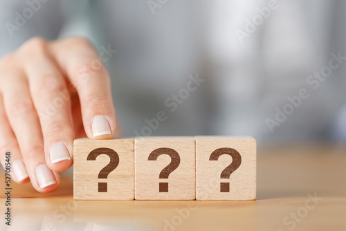 Woman hand holding wooden cube block with question mark.