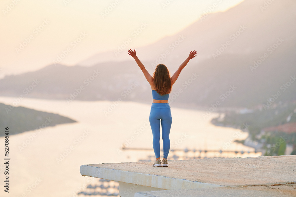 Free inspired motivational fitness woman with open arms standing alone on top at sunset. Enjoying silence moment life, solitude and healthy minds Free inspired motivational fitness woman with open arms standing alone on top at sunset. Enjoying silence moment life, solitude and healthy minds