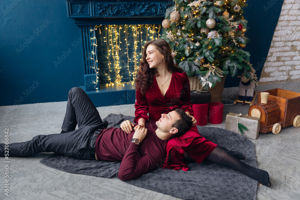 couple in love lying on the blanket and looking away on the background of Christmas tree and fireplace. couple in love lying on the blanket and looking away on the background of Christmas tree and fireplace.