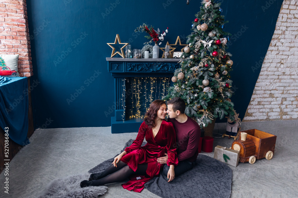 boyfriend and girlfriend hugging and sitting near Christmas tree boyfriend and girlfriend hugging and sitting near Christmas tree