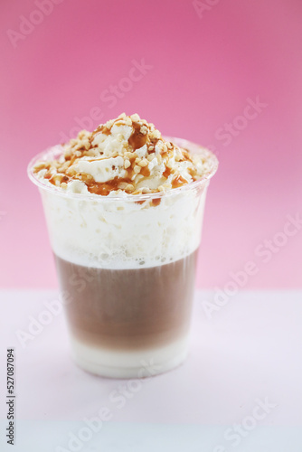 Close view of a tasty caramel milkshake on a pink background.