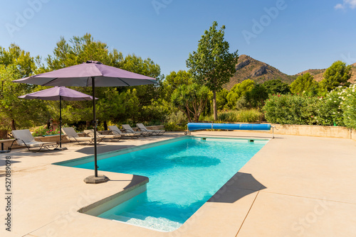 Swimming pool with umbrellas in a country house on a sunny day surrounded by nature and mountains