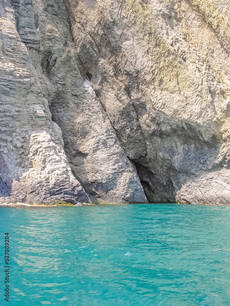 Sheer Cliffs with A Relief Texture Are Reflected in The Turquoise Sea Coastal Water