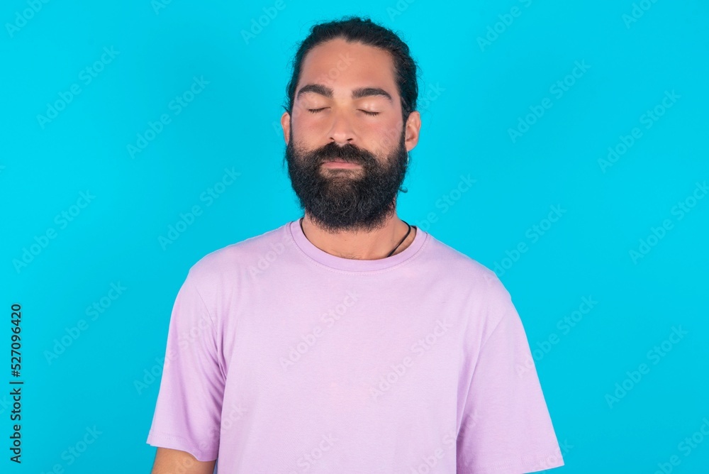young bearded man wearing violet T-shirt over blue studio background nice-looking sweet charming cute attractive lovely winsome sweet peaceful closed eyes young bearded man wearing violet T-shirt over blue studio background nice-looking sweet charming cute attractive lovely winsome sweet peaceful closed eyes