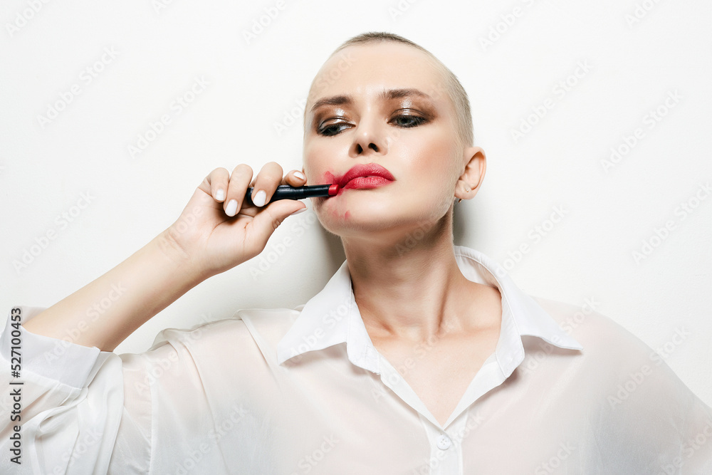 strange woman with short haircut. bald girl smearing red lipstick on her face strange woman with short haircut. bald girl smearing red lipstick on her face