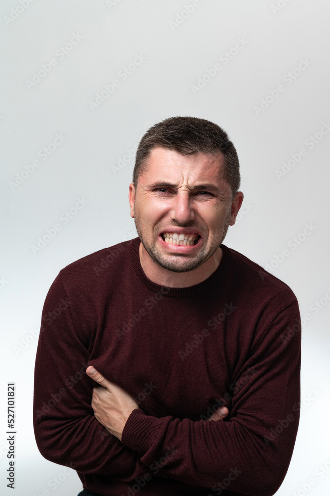 A man touches his stomach with two hands, on a white background with copy space, Stomach pain in a man. A man touches his stomach with two hands, on a white background with copy space, Stomach pain in a man.