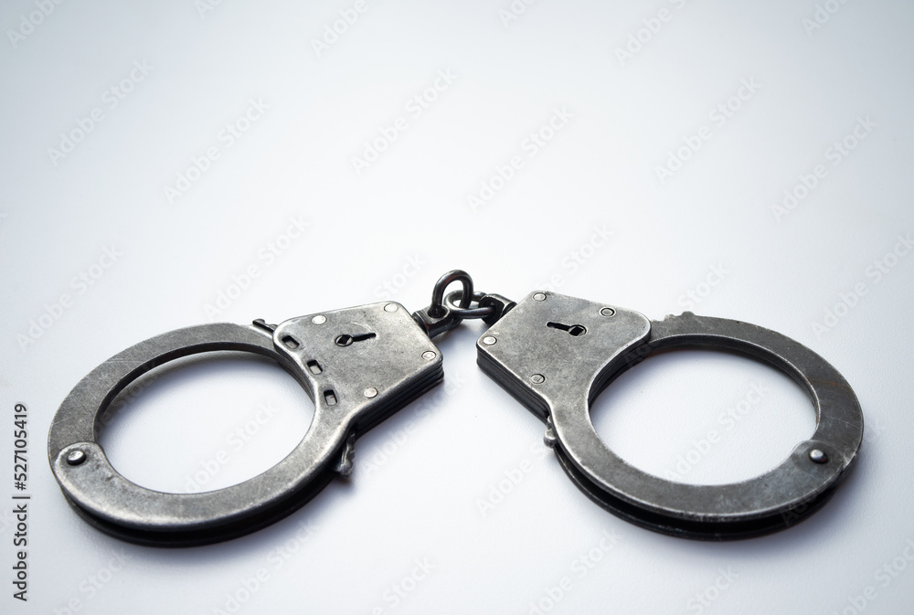 Metal police handcuffs on a white background. Arrest of suspects. Role-playing games with handcuffs.