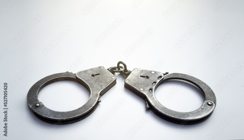 Metal police handcuffs on a white background.News of the arrest. Criminal chronicle. Deprivation of liberty. Metal police handcuffs on a white background.News of the arrest. Criminal chronicle. Deprivation of liberty.