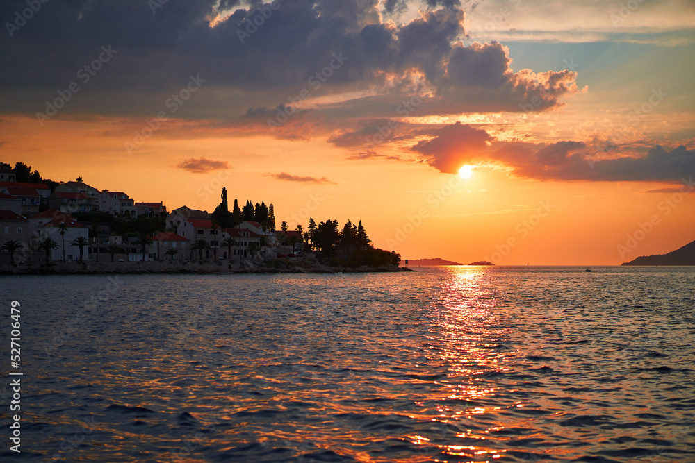 Sunset with dramatic red sky clouds at Korcula island in south Dalmatia over Adriatic sea at the end of hot summer day. Old historic town Korcula is beautiful place to spend summer holiday in Croatia.