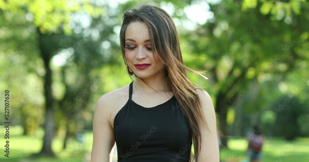 Pretty millennial girl standing looking to camera outside in nature park Pretty millennial girl standing looking to camera outside in nature park
