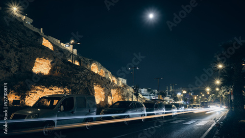 Trails of car headlights driving by enlightened caves carved inside of rock formation. Ancient Kizilkoyun Necropolis in the night time. Sanliurfa city, southeastern Anatolia, Turkey