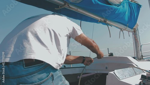 the sailor pulls the rope. the process of raising and lowering the sail. the sailor is working.