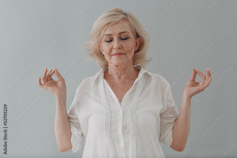 Elderly caucasian old aged woman portrait meditating and smiling with okay gesture Elderly caucasian old aged woman portrait meditating and smiling with okay gesture