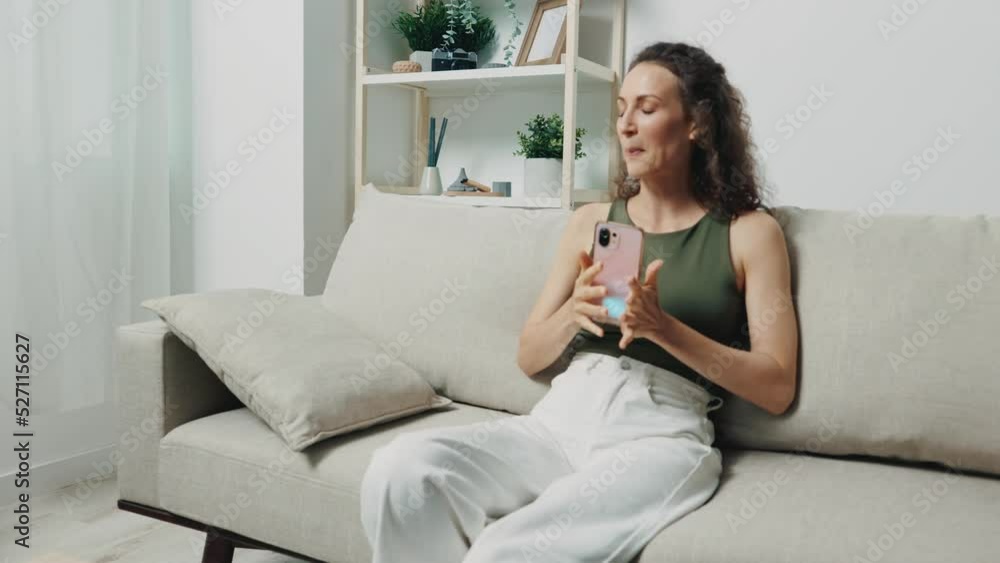 A woman is holding her phone and happily typing a message on the couch at home. Corresponding through the app, virtual communication A woman is holding her phone and happily typing a message on the couch at home. Corresponding through the app, virtual communication