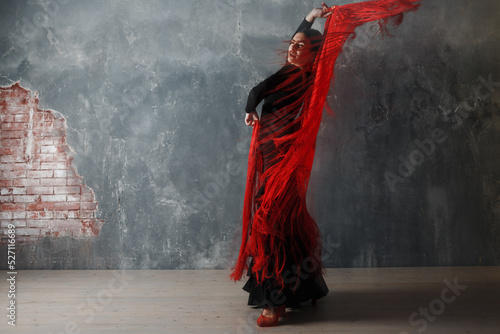 Young adult spanish woman dancing flamenco on grey vintage studio background