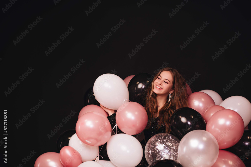 custom made wallpaper toronto digitalA girl with long hair in a black shiny dress celebrates her birthday with a lot of colorful balloons isolated on a black background. Copy space.