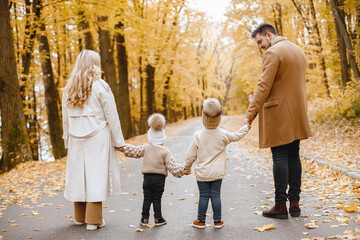 Backside photo of young family on a walk in autumn forest