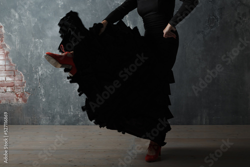 Young adult spanish woman dancing flamenco on gray vintage studio background legs close up