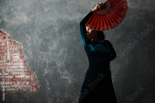 Young adult spanish woman dancing flamenco on gray vintage studio background