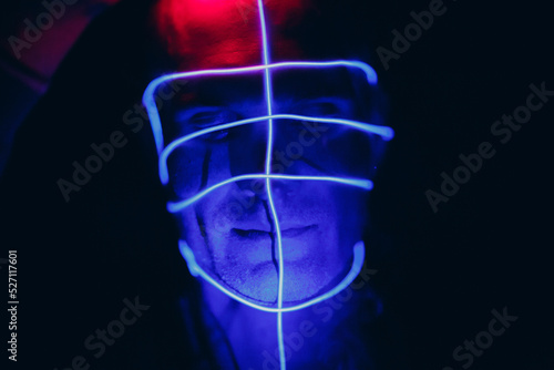 Portrait of man with neon glow lines on his face. Concept cyberpunk and virtual reality © primipil