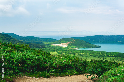 natural landscape of Kunashir island, view of the Golovnin volcano caldera with hot lakes and a path through the thickets of sasa bamboo and dwarf pines on a foreground photo