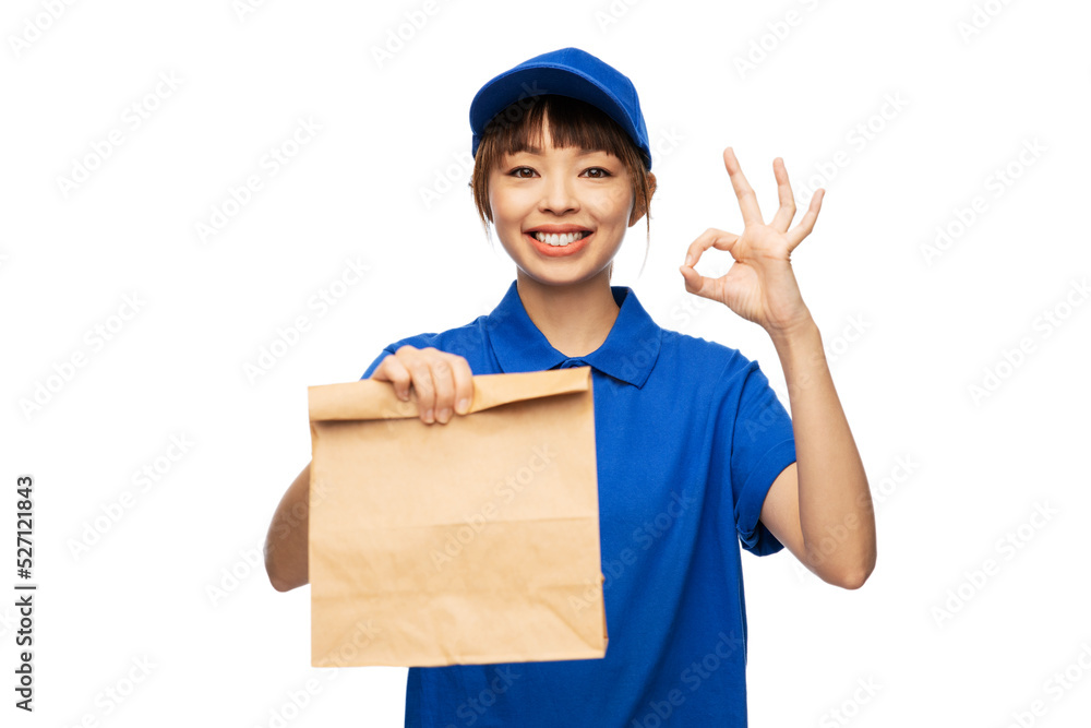 service and job concept - happy smiling delivery woman in blue uniform with takeaway food in paper bag showing ok gesture over white background service and job concept - happy smiling delivery woman in blue uniform with takeaway food in paper bag showing ok gesture over white background