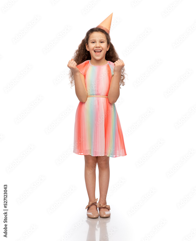 birthday, childhood and people concept - portrait of smiling little girl in dress and party hat making winning gesture over white background