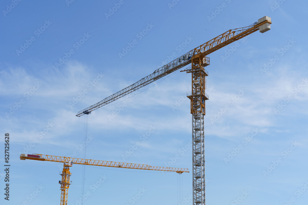Construction cranes against the blue sky. Bottom view. Construction cranes against the blue sky. Bottom view.