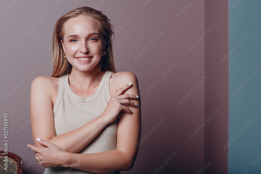 Obraz premium Portrait of young smiling european woman. Beautiful happy blonde girl wears t-shirt and looks at camera. Studio shoot isolated on pink background.
