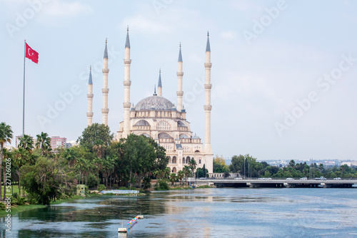 Sabanci Merkez Cami Central Mosque on the Seyhan River with Turkish flags next to it in cloudy weather in Turkey photo