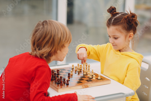 Little kids playing chess at kindergarten or elementary school. Children's chess play